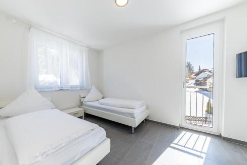 a white bedroom with a bed and a window at Braviscasa - Ferienresidenz Bärenhof Titisee in Titisee-Neustadt