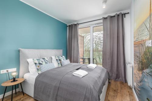 a bedroom with a large bed with blue walls at Apartamenty Wyspa Solna by Renters in Kołobrzeg