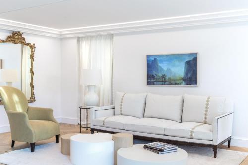 a living room with a white couch and a chair at Airelles Château de la Messardière in Saint-Tropez
