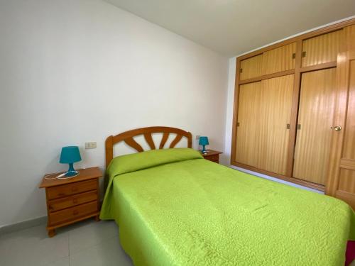 1 dormitorio con cama verde y armario de madera en Apartamentos Irta Playa Altamar, en Alcossebre