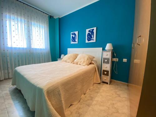 a bedroom with a bed with a blue wall at Apartamentos Playa Del Moro III Altamar in Alcossebre