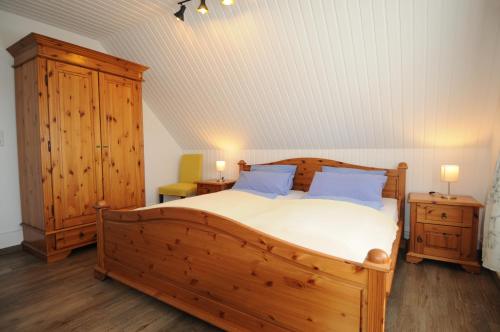 Un dormitorio con una gran cama de madera con almohadas azules en Apartmenthaus am Watt Büsum, en Büsum