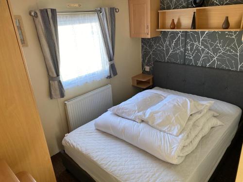 a bed in a small room with a window at 4 bedroom 10 berth caravans with Hot Tub ,Mountain Bikes Tattershall Lakes in Tattershall