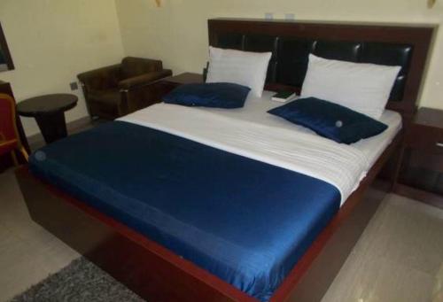 Una cama con dos almohadas azules encima. en Room in Lodge - Dublina Hotels and Suites, en Asaba