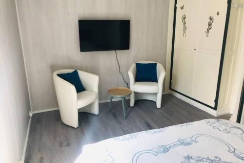 Cette chambre dispose de deux chaises, d'une télévision et d'un lit. dans l'établissement Jolie maison de pêcheur proche plage, au Tréport
