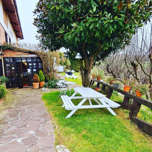 a white picnic table in the grass next to a tree at Hotel Colegiata in Santillana del Mar
