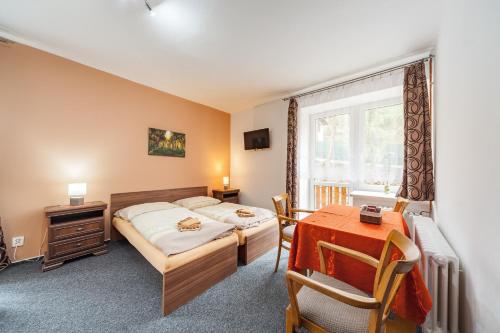 a bedroom with a bed and a table and a window at Penzion U Hráze in Luhačovice