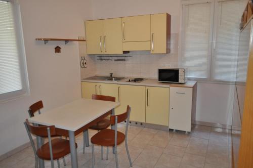 cocina con mesa, sillas y microondas en Residence Paradiso en Laigueglia