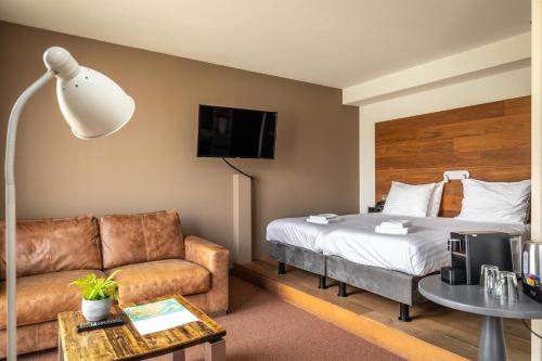 pokój hotelowy z łóżkiem i kanapą w obiekcie Stadshotel Doesburg w mieście Doesburg