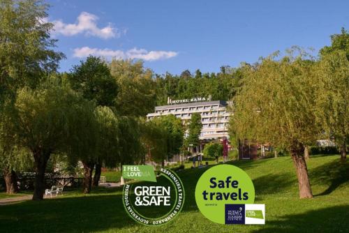 two signs in the grass in front of a building at Postojna Cave Hotel Jama in Postojna