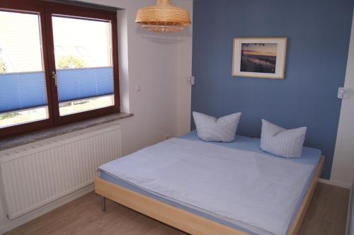 a bedroom with a bed with blue walls and a window at Ferienwohnungen Arkonablick in Lohme