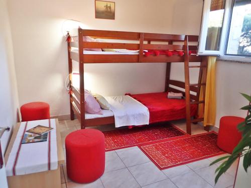 Zimmer mit 2 Etagenbetten und 2 roten Stühlen in der Unterkunft Apartment Blue Ivy near the beach in Jasenice