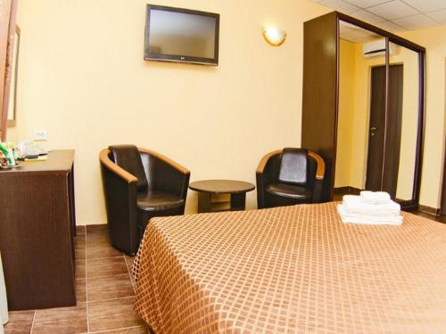 a hotel room with a bed and chairs and a television at Villa Rossa in Rostov on Don