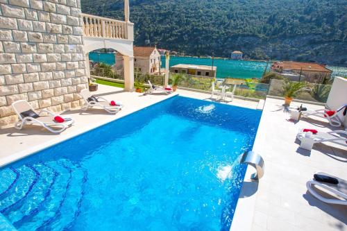 einen Pool mit Stühlen und ein Haus in der Unterkunft Villa Arion in Mokošica