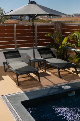 two chairs and an umbrella next to a pool at The Z Private Villa, Santorini in Monolithos