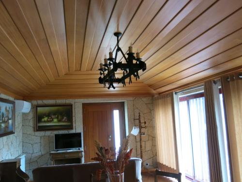 a living room with a wooden ceiling with a chandelier at Casa Dos Tinocos in Braga