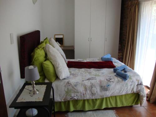a bedroom with a bed and a table with a lamp at Trafalgar Chalets Unit 1 in Southbroom