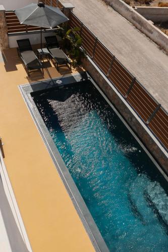 a swimming pool with two chairs and an umbrella at The Z Private Villa, Santorini in Monolithos