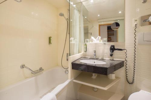 ein Badezimmer mit einem Waschbecken, einer Dusche und einer Badewanne in der Unterkunft Hotel Adler Zürich in Zürich