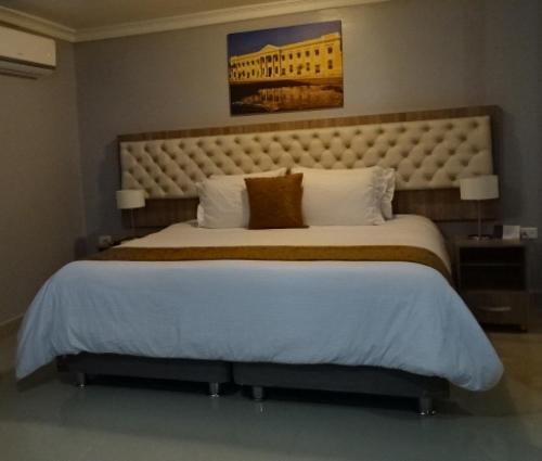 a bedroom with a large bed with a large headboard at Hotel Prado Real in Barranquilla
