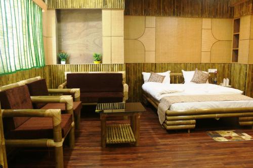 a bedroom with a bed and a couch and a chair at Hotel Himalaya in Agartala