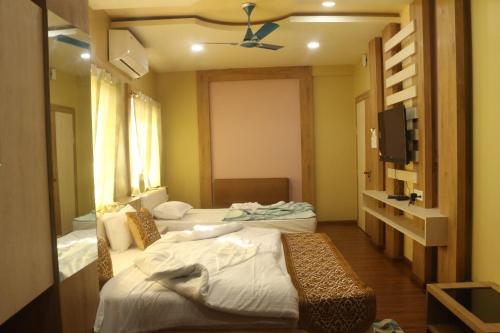 a hotel room with two beds and a tv at Hotel Himalaya in Agartala