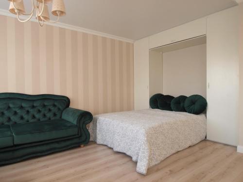 1 dormitorio con 1 cama y 1 sofá verde en Apartment Akropolis Studio1, en Klaipėda