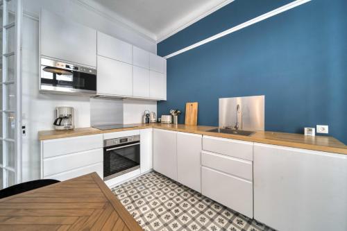 une cuisine avec des armoires blanches et un mur bleu dans l'établissement Cannes Luxury Rental - Apartment City Center, à Cannes