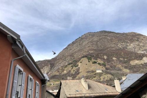 a mountain with a bird flying over a building at Le Reflet de la Lune in Saint-Jean-de-Maurienne