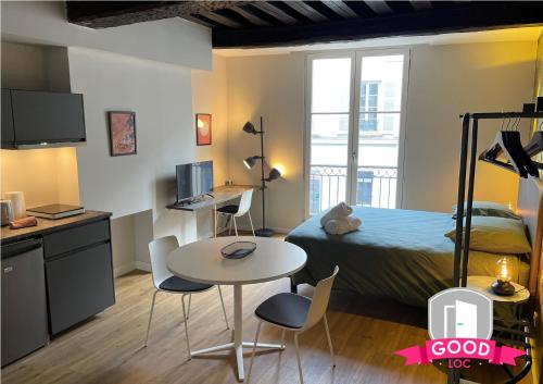 a small room with a bed and a table and chairs at Somptueux studio Hyper Centre avec WIFI in Orléans