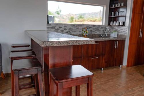 a kitchen with a counter and a sink and stools at Chalet Familiar Full equipado! Jacuzzi privado 30 minutos gratis! in Sogamoso