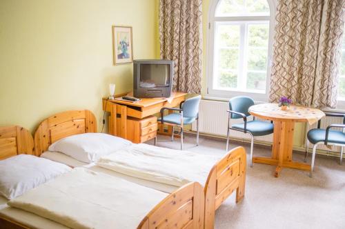 Cette chambre comprend deux lits, un bureau et une télévision. dans l'établissement Bürgerhaus auf dem Hasenberg, à Gützkow