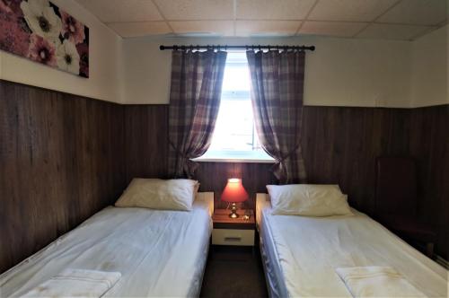 two beds in a small room with a window at The Hopton Hotel in Blackpool