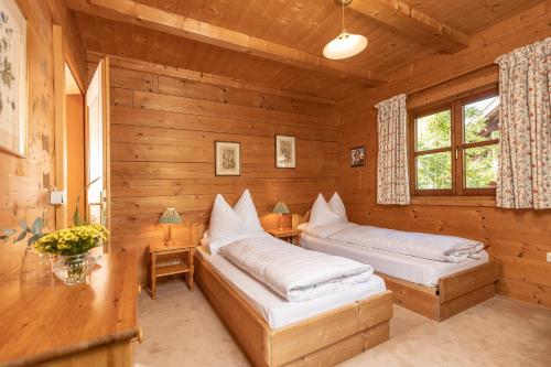 two beds in a wooden room with a desk and window at Chalet Innerhof in Alpbach