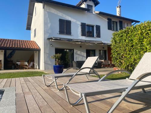 two lawn chairs sitting on a wooden deck in front of a house at Hiru Alabak - Maison à Biarritz, piscine, jardin, 8 personnes in Biarritz