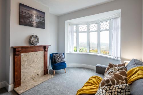 een woonkamer met een bank en een open haard bij Blue Rose Cottage in Burry Port
