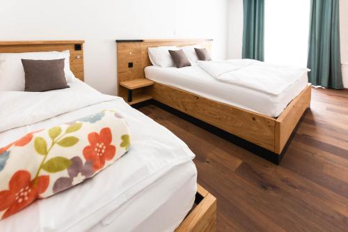 two beds in a room with wood flooring at HIŠA KOSOBRIN in Kranjska Gora
