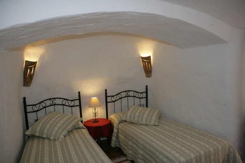 a bedroom with two beds and a red table with a lamp at Casas Cueva el Mirador de Orce in Orce
