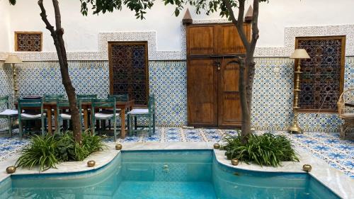 - une piscine dans un restaurant avec une table et des chaises dans l'établissement Riad Yamina, à Marrakech