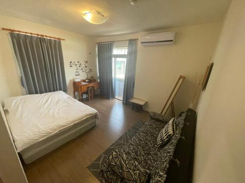 a bedroom with a bed and a couch in a room at Sigang Vacation Homestay in Xigang