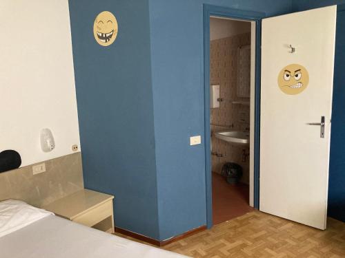 a bedroom with a blue wall with two faces on the door at Route77 hostel in Toscolano Maderno
