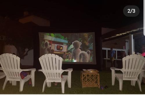 a group of white chairs in front of a screen at Cabañas Las Pencas in Mina Clavero