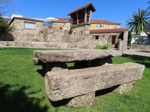 a stone bench sitting in the grass in front of a building at Casa Ventura in César