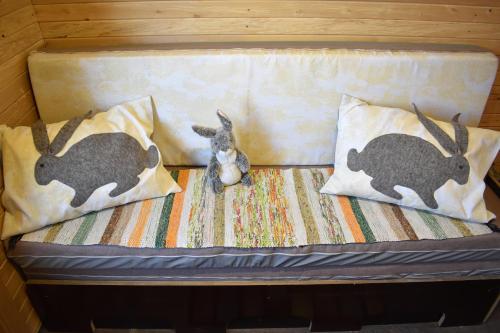 Una cama con dos almohadas y un conejo de peluche. en Usmas zaķīšu pirtiņa - Bunny house en Usma