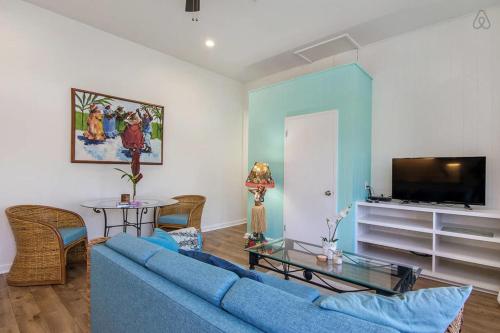 a living room with a blue couch and a tv at Turtle Cottage in Kailua