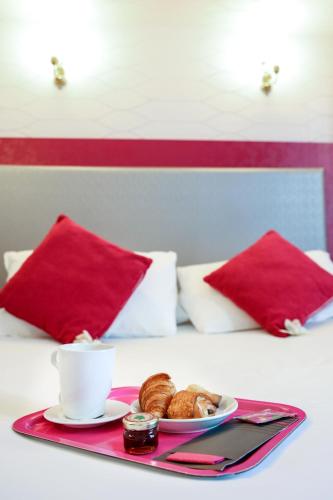 a tray with a cup of coffee and pastries on a bed at HOTEL DE PARIS MONTPARNASSE in Paris