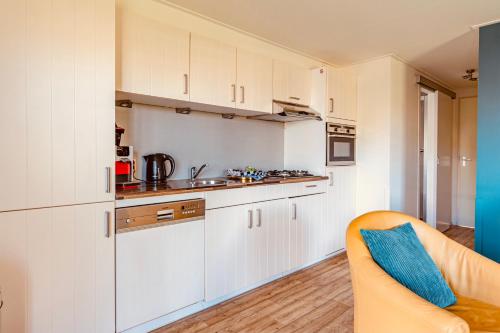 a kitchen with white cabinets and a blue pillow on a couch at Chalet park Kroondomein Giethoorn in Giethoorn