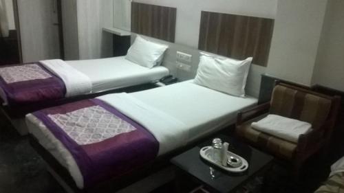 two beds in a room with a table and a chair at R.J.Residency in Ahmedabad