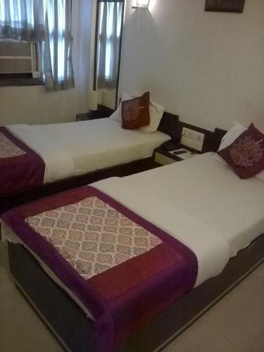 two beds sitting next to each other in a room at R.J.Residency in Ahmedabad