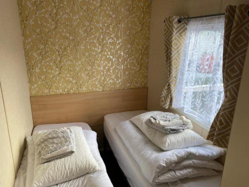 a small room with two beds and a window at 3 bedroom 8 berth standard caravans with Hot Tub,Mountain Bikes in Tattershall